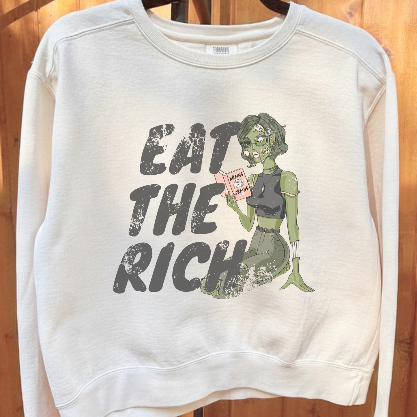 Eat the Rich zombie Halloween sweatshirt with feminist political satire graphic, relaxed cropped fit, and cozy fleece interior for spooky season.