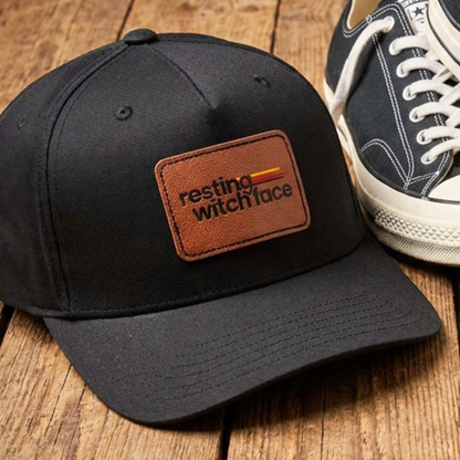 Resting Witch Face baseball hat featuring a light brown vegan leather rectangle patch with funny feminist witch design and vintage-inspired style.