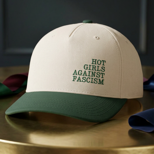 Hot Girls Against Fascism green and natural baseball cap with embroidered feminist design, structured mid-profile crown, green brim, and adjustable snap closure.