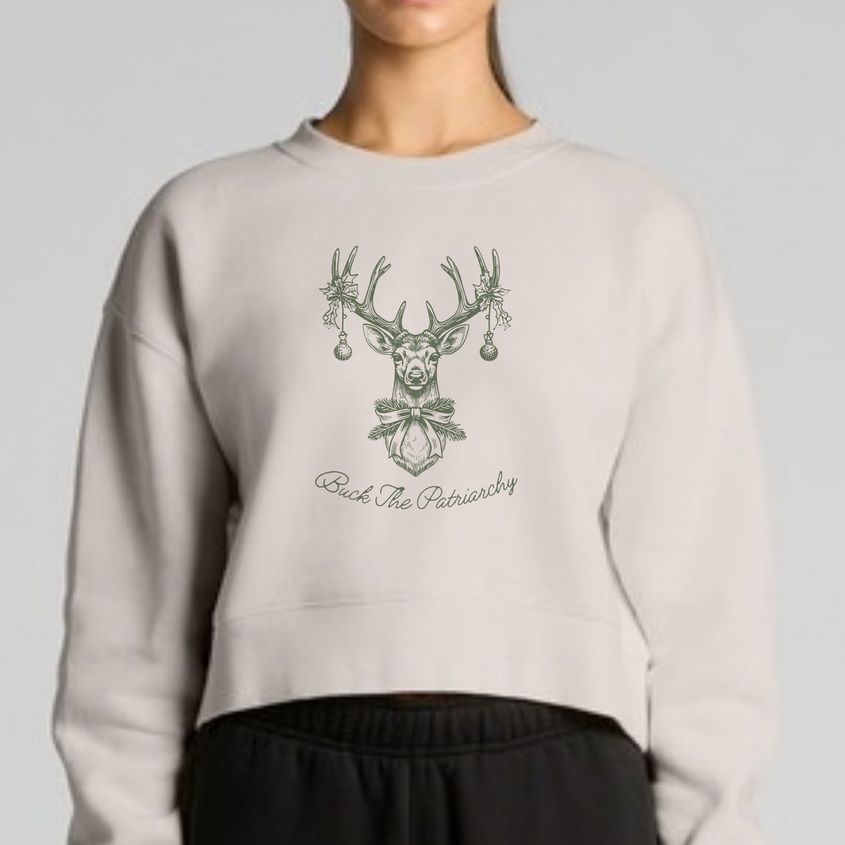 A model wearing a light gray cropped sweatshirt with a green deer graphic and the text 'Rock The Punisher' on the front, paired with black sweatpants, against a solid light gray background.